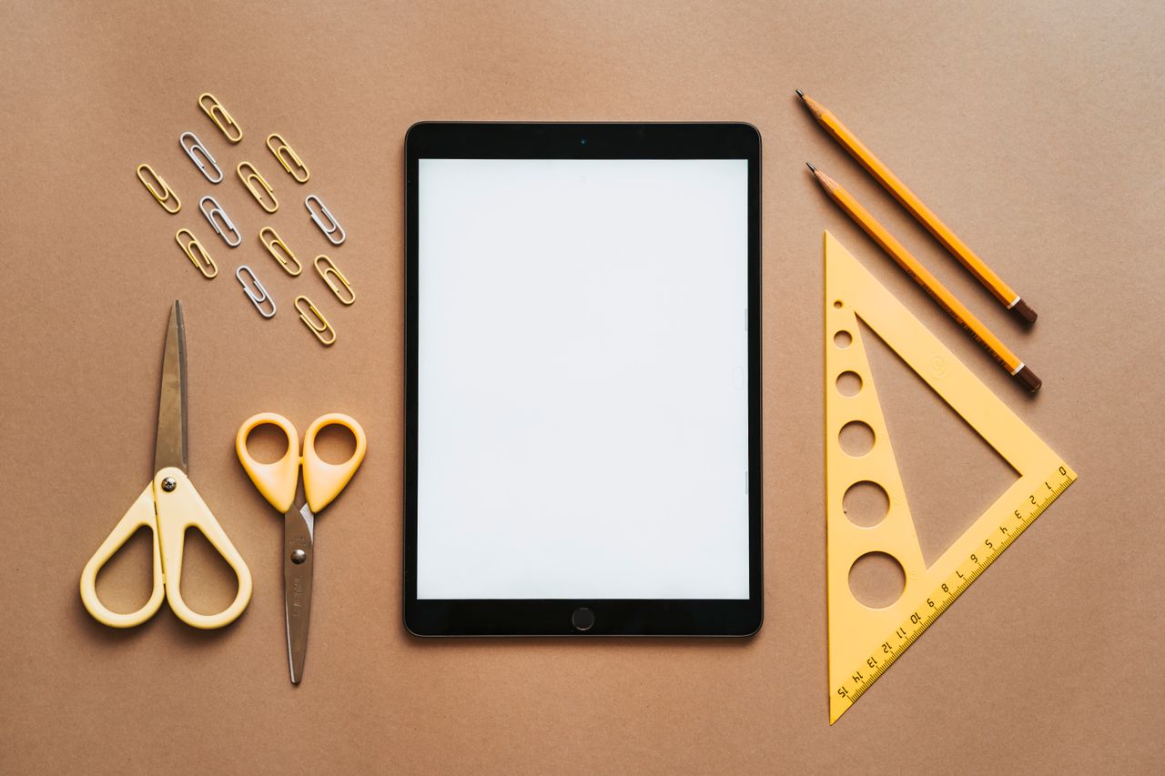 Stationery arranged with tablet on brown background.